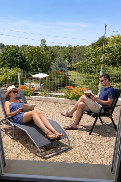 Couple détente dans les transats du gîte Le Petit Moulin à Pouzauges, avec vue sur les jardins et la campagne
