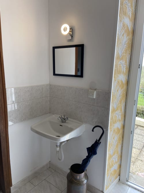 Lavabo de salle de bains avec miroir et applique murale au Petit Moulin B&B, Pouzauges