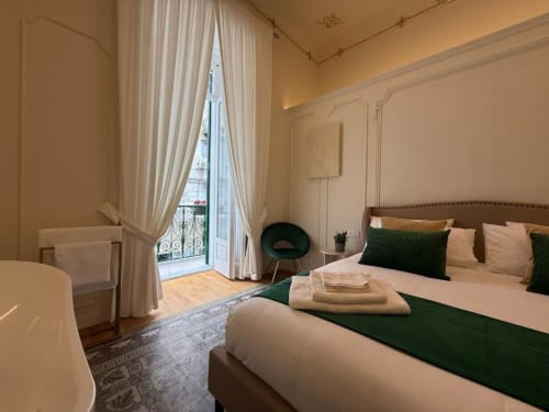 Elegante suite presso Residenza Seconnino a Napoli con balcone vista città, letto king size con runner verde e stile parigino classico