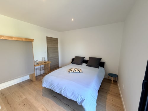 Chambre lumineuse à l'Hôtel CARPE DIEM à Lorgues avec lit queen, oreillers foncés, mobilier en bois et vue sur le jardin