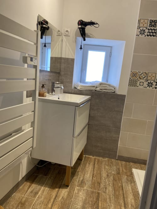 Salle de bain moderne du Petit Moulin B&B à Pouzauges avec vasque blanche, sèche-serviettes chauffant et carrelage décoratif