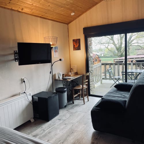 Studio cozy au gîte Le Petit Moulin à Pouzauges avec plafond en bois, télévision, bureau et vue sur la terrasse