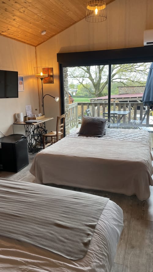 Chambre moderne au Petit Moulin avec lits jumeaux, plafond en bois et vue panoramique sur la campagne