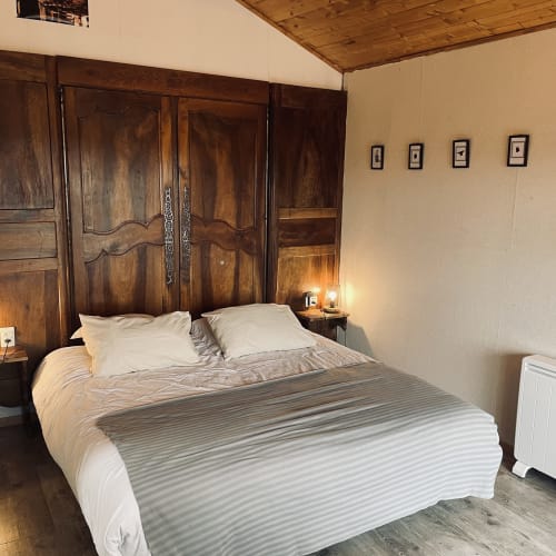 Chambre douillette au Gîte Le Petit Moulin à Pouzauges avec tête de lit en bois et literie rayée