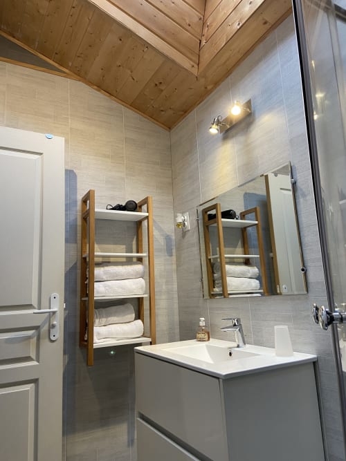 Salle de bains moderne au Petit Moulin avec étagères en bois, lavabo, miroir et plafond en bois