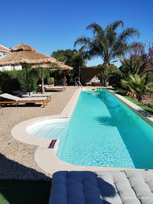 Turquoise swimming pool with spa at MontePico hotel in Grândola, Portugal, surrounded by loungers and tropical gardens