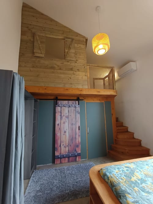 Chambre Castellas à La Vigneronne Des Costières avec mezzanine en bois, escalier et suspension jaune à Vauvert