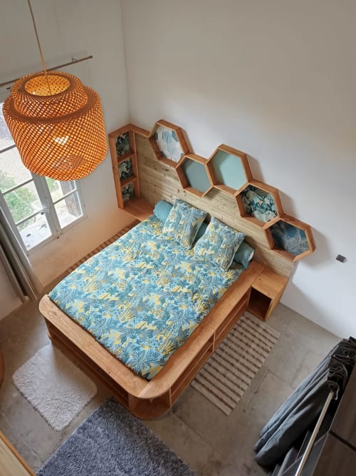 Chambre cosy à La Vigneronne Des Costières avec lit en bois, parure bleue à motifs, étagères hexagonales et suspension tressée