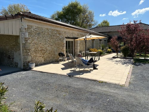 Terrasse en pierre du gîte Le Jardin d'Elusa à Eauze avec chaises longues et parasol jaune par beau temps