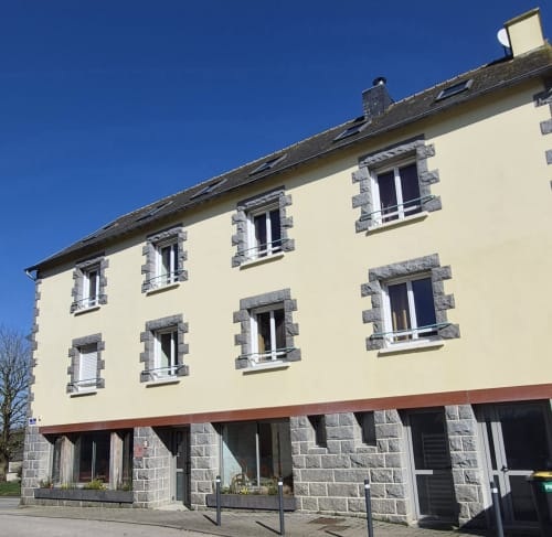 Hôtel Aux Genêts d'Or à Trévé, France - façade en pierre et crème avec grandes fenêtres et toit d'ardoise
