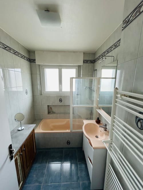 Salle de bain moderne avec baignoire, cabine de douche, lavabo pêche, sèche-serviettes chauffant et carrelage foncé à LA CONCIERGERIE DES