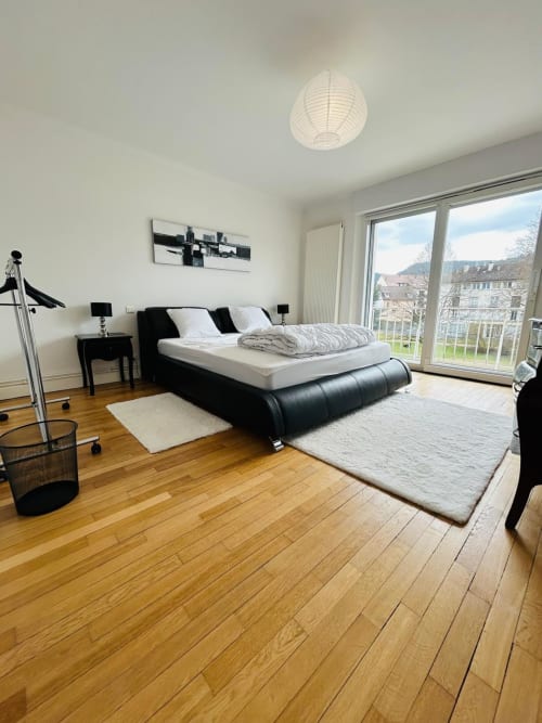 Chambre moderne avec lit noir, parquet, balcon vue sur lac à l'appartement de Gérardmer