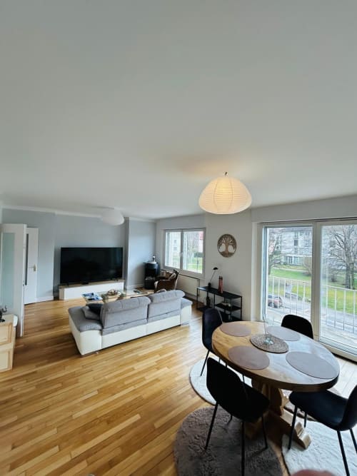 Séjour lumineux à Gérardmer avec vue sur le lac, salle à manger, canapé, téléviseur et mobilier moderne