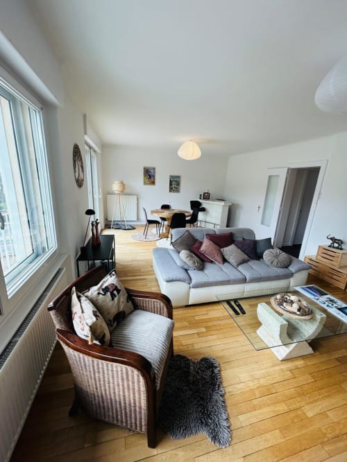 Appartement lumineux à Gérardmer avec vue sur le lac, canapé moderne, coin repas et grandes fenêtres inondées de lumière naturelle