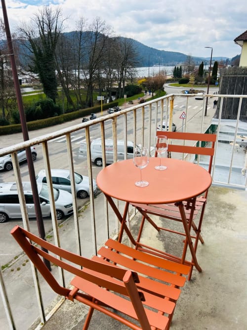 Mobilier de bistrot orange sur balcon avec vue sur le lac de Gérardmer et les montagnes, La Conciergerie des Lacs