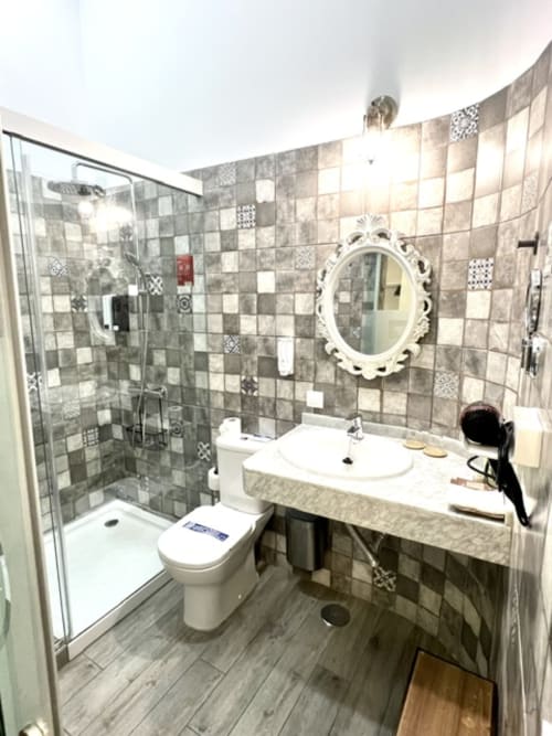 Modern bathroom at Hotel The Cathedral Vegueta with walk-in shower, white sink, and patterned tile walls in Las Palmas