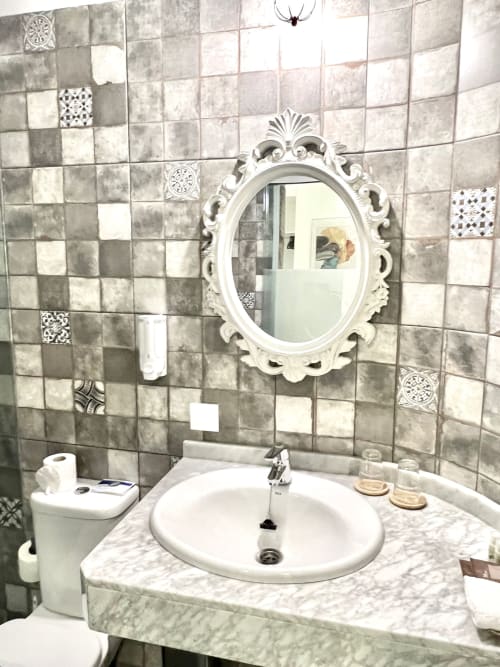 Elegant bathroom with marble vanity, white ornate mirror, and patterned tile wall at Hotel The Cathedral Vegueta, Las Palmas
