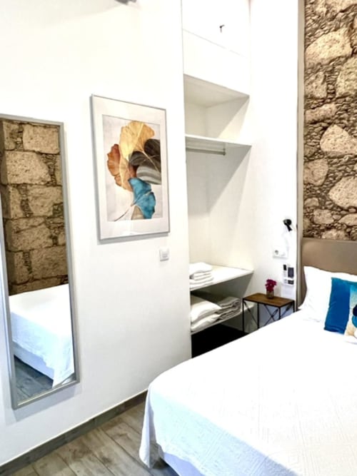 Modern double bedroom at Hotel The Cathedral Vegueta with stone walls, white built-in storage, and contemporary furnishings