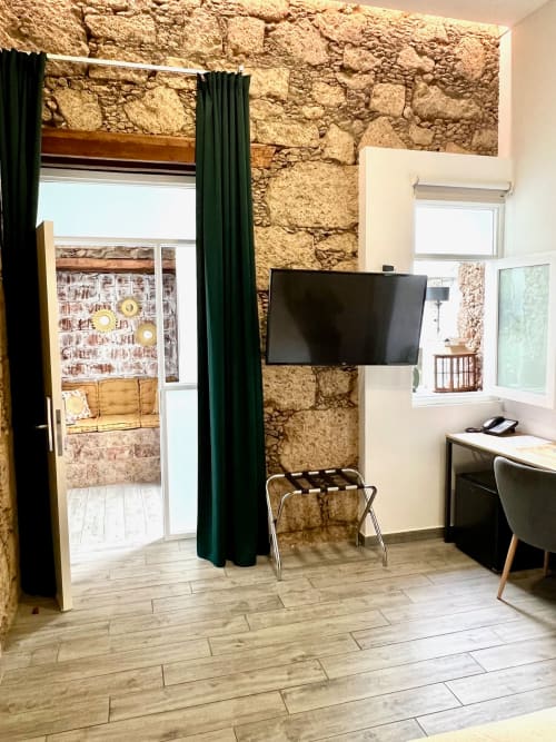 Modern hotel room at The Cathedral Vegueta with stone walls, flat-screen TV, work desk, and furnished with contemporary decor