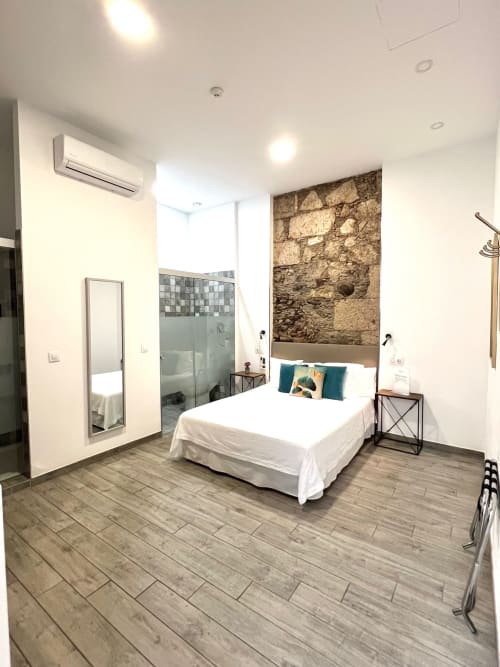 Habitación deluxe en The Cathedral Vegueta con cama queen, pared de piedra, baño privado y comodidades modernas en Las