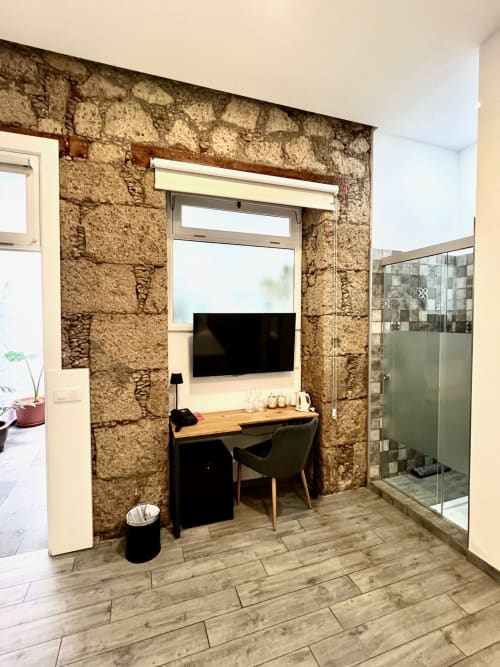 Habitación Deluxe en Hotel The Cathedral Vegueta con muros de piedra vista, TV de pantalla plana, escritorio de madera y moderno baño con ducha