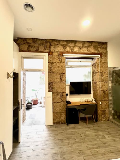 Habitación Deluxe del Hotel The Cathedral Vegueta en Las Palmas con escritorio, televisor, muros de piedra vista y baño