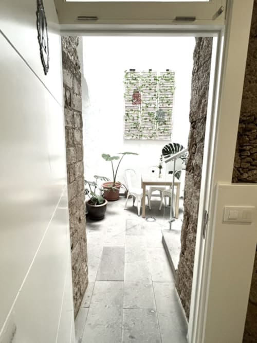 Habitación Deluxe en Hotel The Cathedral Vegueta con balcón soleado, plantas en macetas y vistas sobre muros de piedra