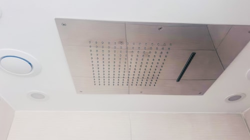 Nowoczesna deszczowa głowica prysznicowa montowana na suficie z metalicznym wykończeniem w apartamencie S'Incantu w Sardegna Explora House, Magomadas