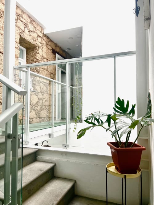 Balcón moderno con barandales de cristal en Hotel The Cathedral Vegueta, Las Palmas, con planta en maceta y arquitectura de piedra