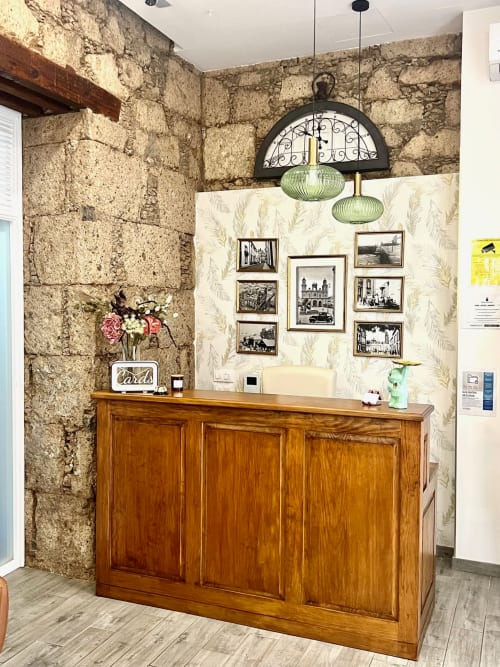 Recepción del Hotel The Cathedral Vegueta con mostrador de madera, muros de piedra y fotografías enmarcadas en Las Palmas