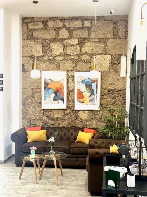 Lounge moderno del Hotel The Cathedral Vegueta con pared de piedra, sofá oscuro, cojines coloridos y arte botánico.