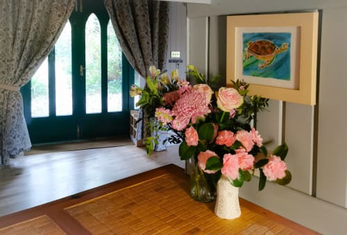 Elegant entrance hall at Kilmokea Country Manor with pink flowers, framed turtle artwork, and arched green door overlooking