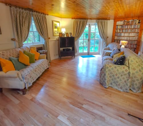 Spacious living room at Kilmokea Country Manor's Garden House cottage in Wexford with sofas, fireplace, bookshelves, and