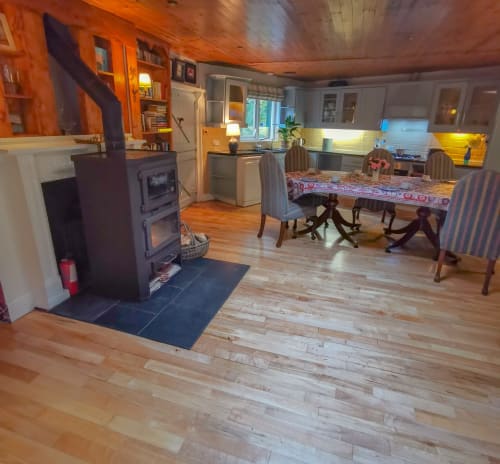 Open-plan living area in The Garden House cottage at Kilmokea Country Manor with dining table, wood stove, and kitchen