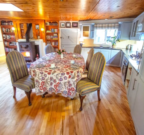 Garden House cottage dining area with round table, striped chairs, wooden ceiling, and kitchen at Kilmokea Country Manor,