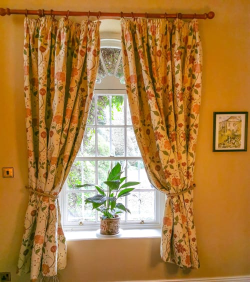 Bright yellow room with floral curtains framing a window at Kilmokea Country Manor garden cottage in Wexford, Ireland