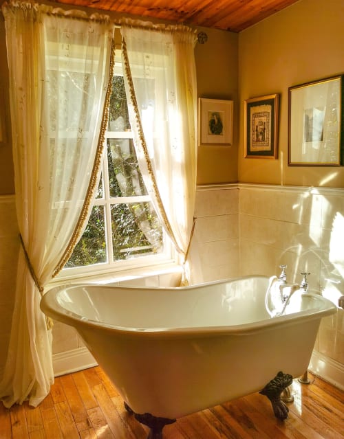 Luxurious standalone bathtub by window with garden views at Kilmokea Country Manor cottage in Wexford, Ireland