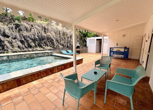Espace piscine de la Villa Adele avec terrasse couverte, chaises longues turquoise et paysage verdoyant à La Conciergerie