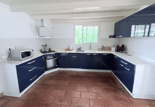 Cuisine moderne avec armoires bleu marine, comptoirs blancs et carrelage en terre cuite à la Villa Adèle en Martinique