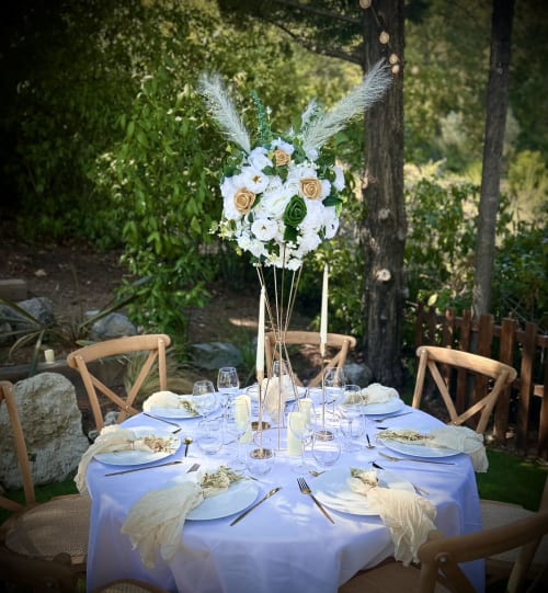 Élégante table dressée en plein air à La Villa Tosca à Callian, fleurs blanches, nappe bleue et forêt en arrière-plan