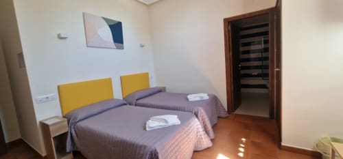 Habitación doble del Hotel Atalaya en Guadalupe con camas gemelas, cabeceros amarillos y decoración moderna