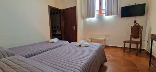 Habitación doble en Hotel Atalaya de Guadalupe con televisor, muebles de madera y piso de barro