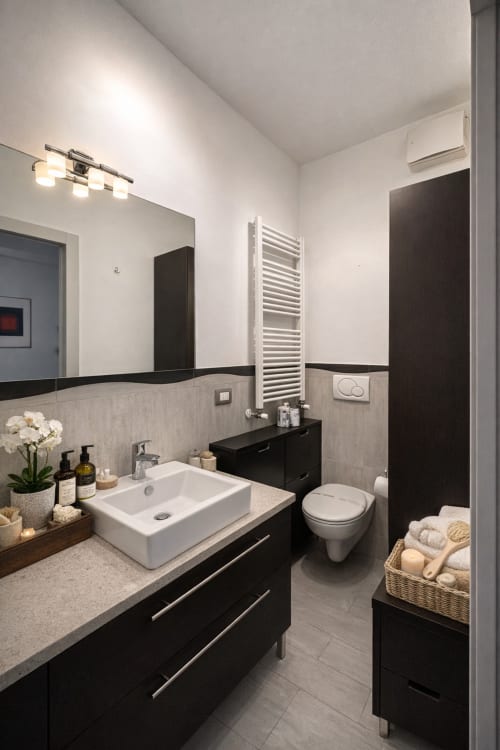 Modern bathroom in Hbhall Navigli Milano apartment with black vanity, white sink, and heated towel rack