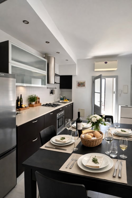 Modern black and white kitchen-dining area in Milano apartment with elegant place settings and stainless steel appliances