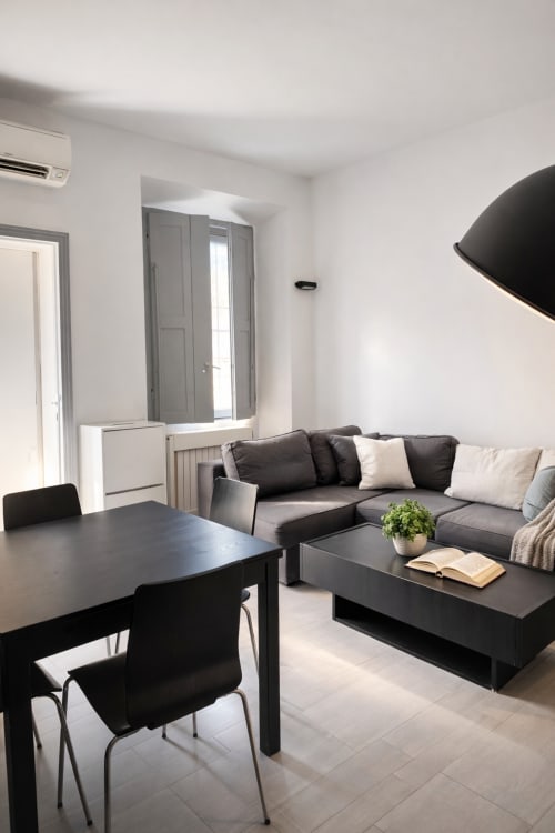 Modern Milano apartment living room with black sofa, dining table, and floor-to-floor windows at Hbhall Navigli 15