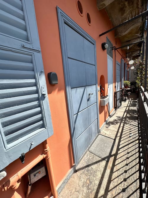 Bright orange building exterior with blue-gray doors and shutters in Milano's Navigli district, apartment entrance with black