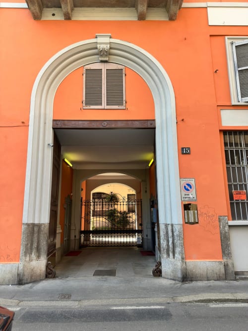 Hbhall Navigli 15 apartment entrance in Milano, featuring vibrant orange facade and arched doorway