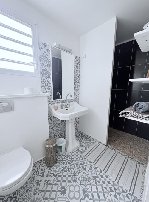Salle de bain moderne à l'appartement Mango Trees de La Conciergerie Martinique avec carrelage motifs, lavabo sur colonne et carrelage noir