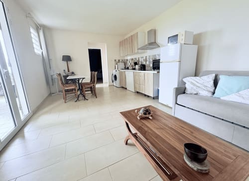 Appartement Mango Trees à La Conciergerie Martinique : séjour ouvert avec canapé, cuisine, table à manger et accès à la vue sur mer