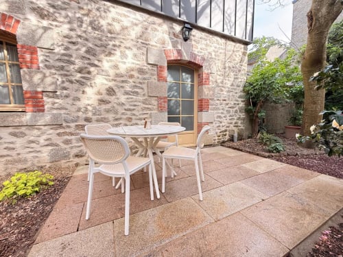 Mobilier de patio blanc sur la terrasse du gîte Chez David et Sara à Pontivy, avec façade en pierre et vue sur le jardin
